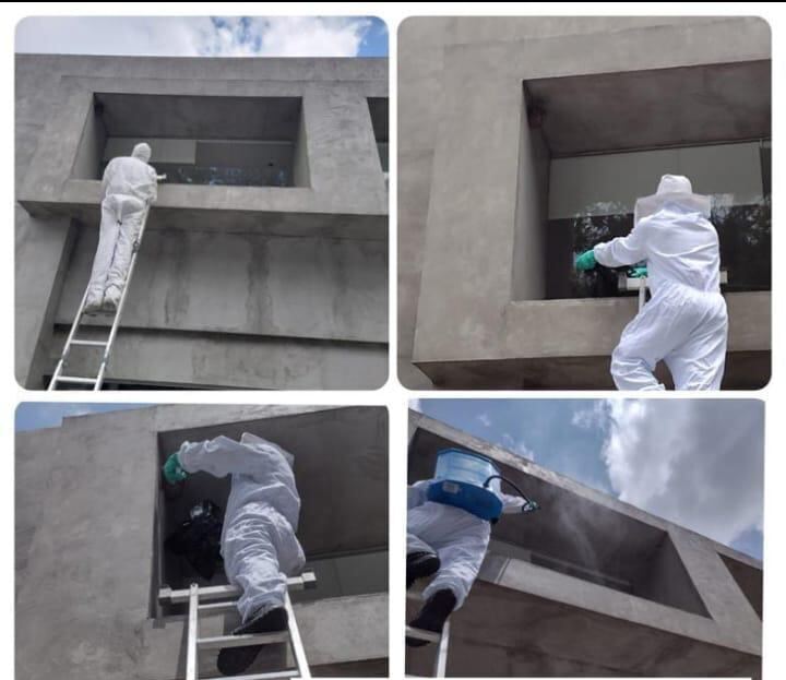 Equipe realizando dedetização externa em fachada comercial com escada e EPI